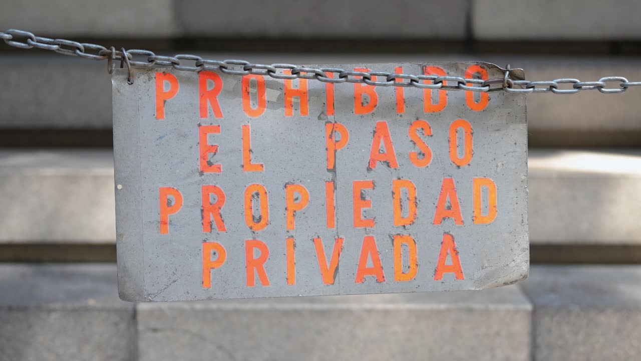 Close-up on a weathered, stenciled sign that reads "Prohibido El Paso." A gritty, urban visual representing forbidden access, neglect, and decay