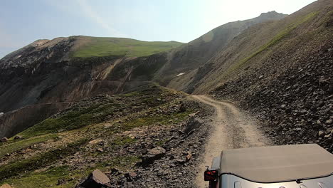 punto de vista sobre el capó del vehículo en un sendero estrecho fuera de la carretera que sube por una pequeña elevación y se abre a un valle profundo