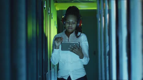 african american female computer technician using tablet working in business server room