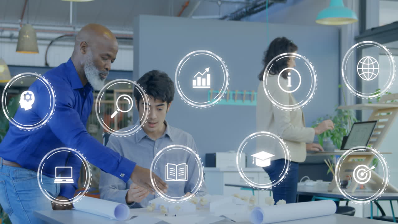 Animation of multiple digital icons against two diverse men discussing over a plan at office