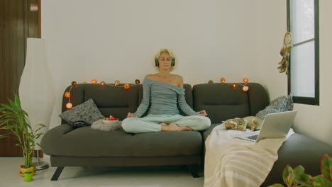 woman meditating at home with cat and laptop