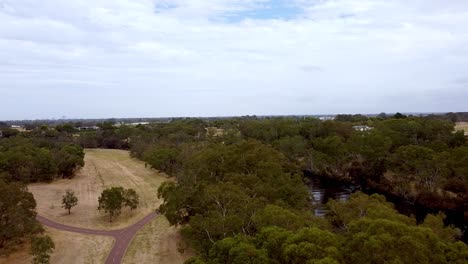 Panning-shot-right-to-left-above-a-green-valley-with-cyclepaths-and-a-river