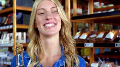 personal femenino sonriente sosteniendo una botella de aceite de oliva en un supermercado