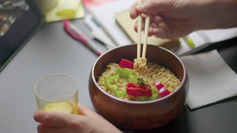 Man-enjoy-vegan-organic-tasty-delicious-ramen-noddles-healthy-balanced-diet-at-work-lunch-break-while-watching-movie-tablet-ipad-close-up-shot