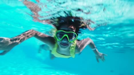 happy girl in goggles swim underwater in pool. close up.