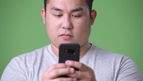 young handsome overweight asian man against green background