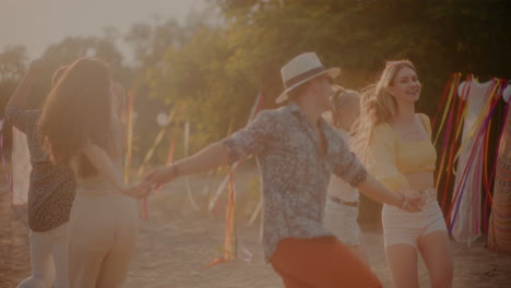 hombres y mujeres felices tomados de la mano y bailando en la playa