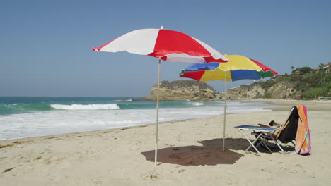 Klappstuhl-Und-Bunte-Sonnenschirme-Am-Leeren-Strand-An-Einem-Sonnigen-Sommertag