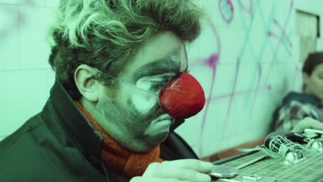 payaso sentado con una maleta en el metro urbano
