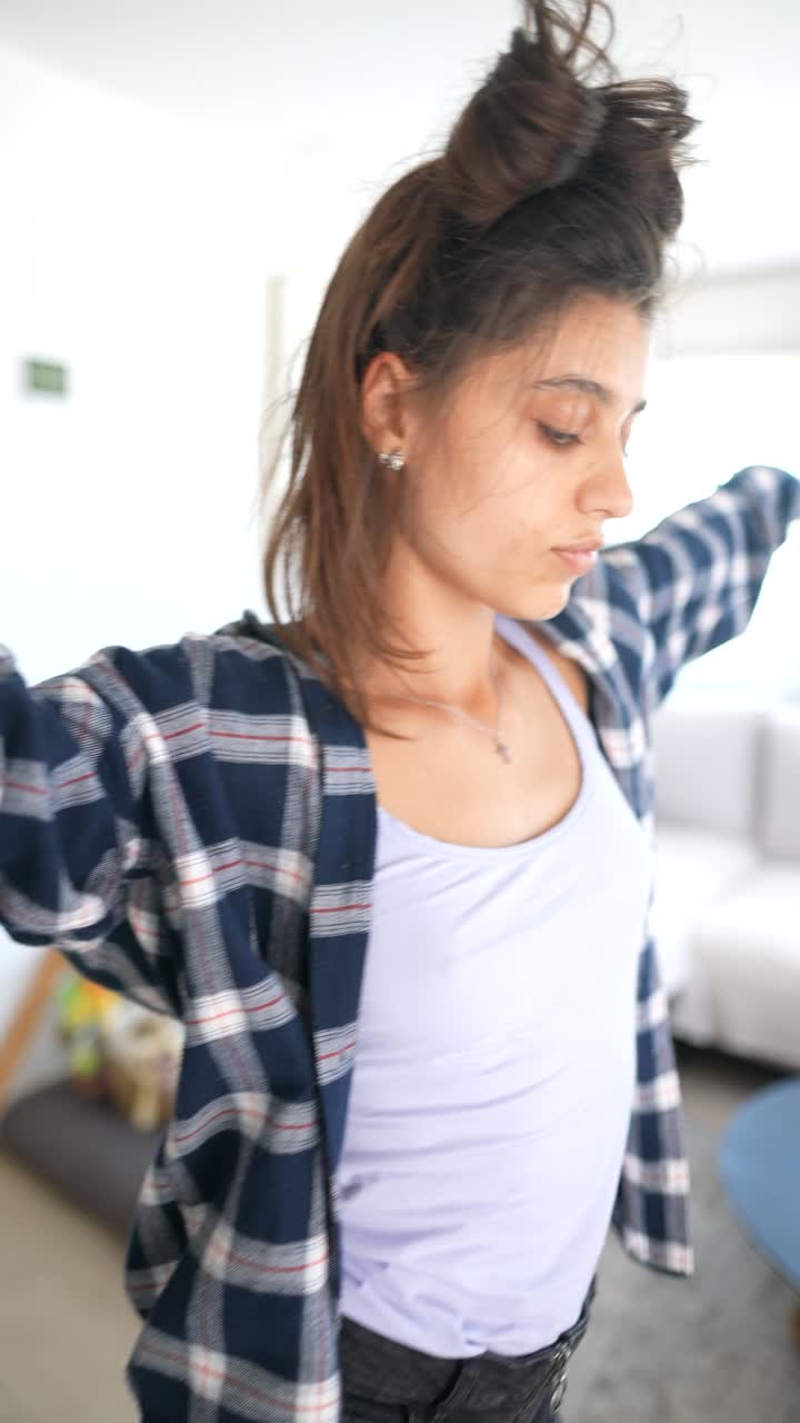 una mujer joven bailando en casa.