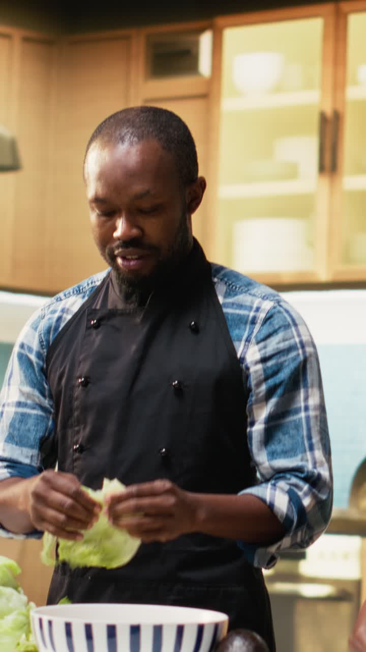 Vertical Video African american man ripping and washing lettuce leaves for a salad