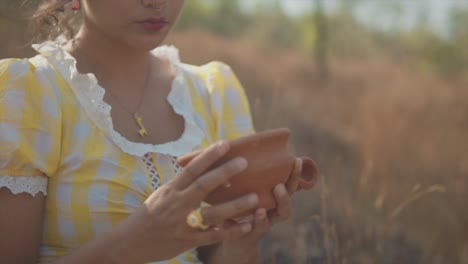 zoom nostálgico en cámara lenta de una joven hermosa mujer india mirando hacia abajo a una olla de arcilla en sus manos