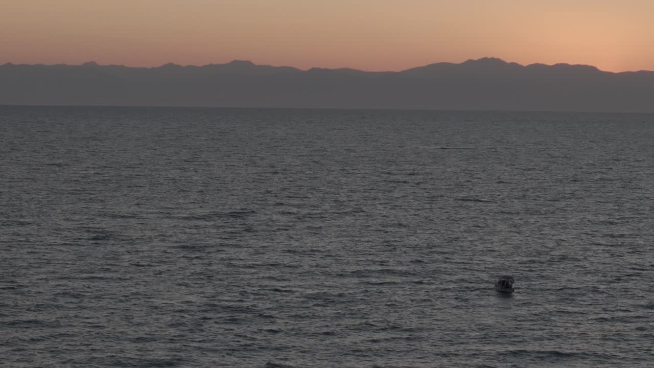 빛나는 오렌지색 터키 해가 지는 하늘 아래 평화로운 지중해를 가로질러 여행하는 작은 관광 항해 보트