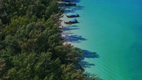 aerial drone shot moving left to right, revealing a pristine tropical beach on koh kradan, thailand, with turquoise waters, lush greenery, white sand, and traditional long-tail boats in 4k.