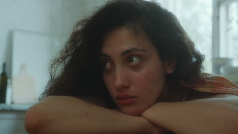 depressed girl resting her head on arms at kitchen table
