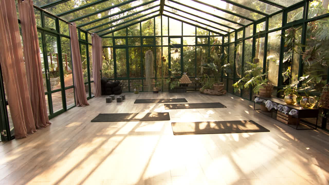 Yoga mats arranged in glass house for serene yoga practice amidst nature