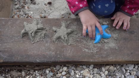 young girl in pink shoes makes starfish in the fine adriatic sand