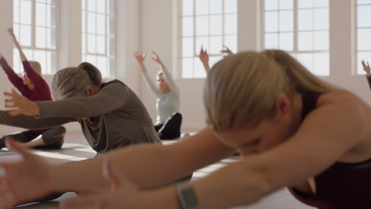 yoga-kurs einer gesunden, reifen frau, die die vorwärtsbeuge-pose von kopf bis knie übt und das morgendliche körperliche fitnesstraining im studio genießt