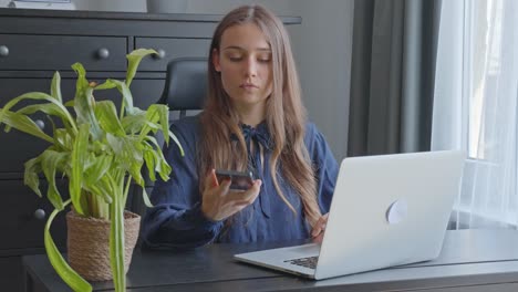 Young-woman-in-a-modern-grey-office-picking-up-phone-call,-in-Slow-Motion