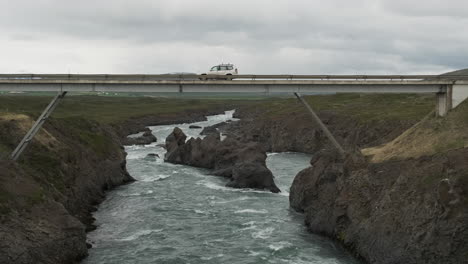 cars driving across rocky river on a small rural bridge