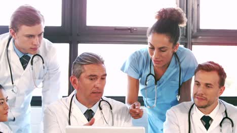 equipo médico hablando juntos mientras miran portátil