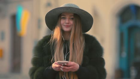 woman in a bright sunlight uses her phone while standing in the city center