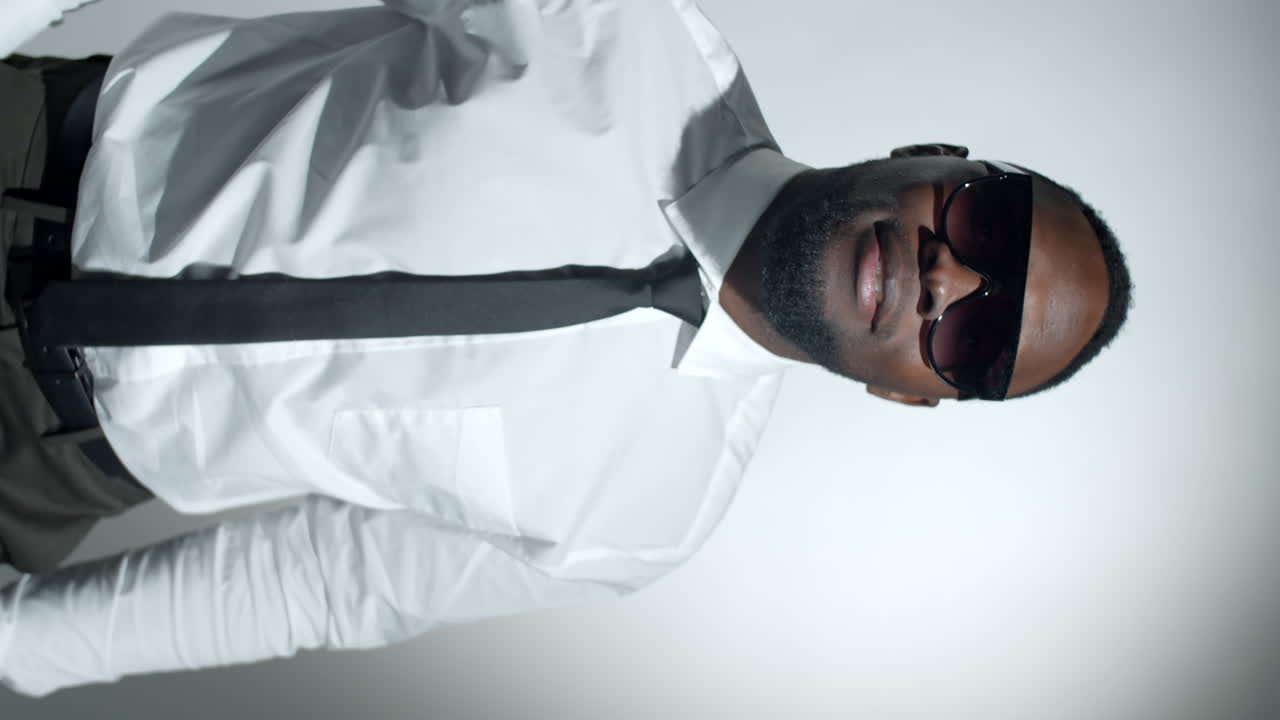 선글라스를 입은 세련된 흑인 남자가 카메라에 미소 짓고 있다.