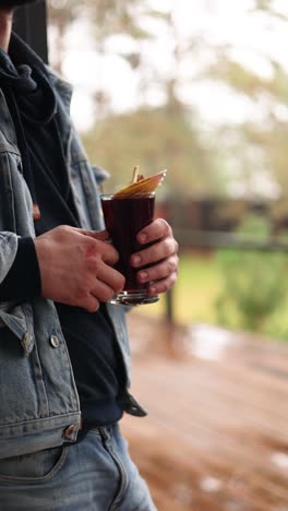 man holding a mug of hot mulled wine outdoors