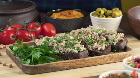 israeli cuisine. hands taking forshmak with black rye bread decorated with parsley close-up. national jewish herring dish, middle eastern culture. traditional snack vorschmack made of fish fillet