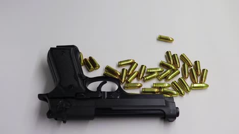 persona colocando un cargador de armas de fuego al lado de un arma de fuego negra rodeada de balas