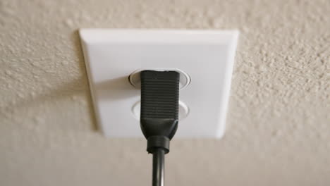 close up of man's hand plugging cord into electrical outlet then unplugging in slow motion