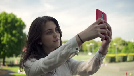 jovem italiana com smartphone tirando selfie ao ar livre em um parque em londres