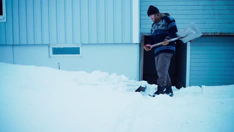 man clearing deep snow with shovel - wide shot