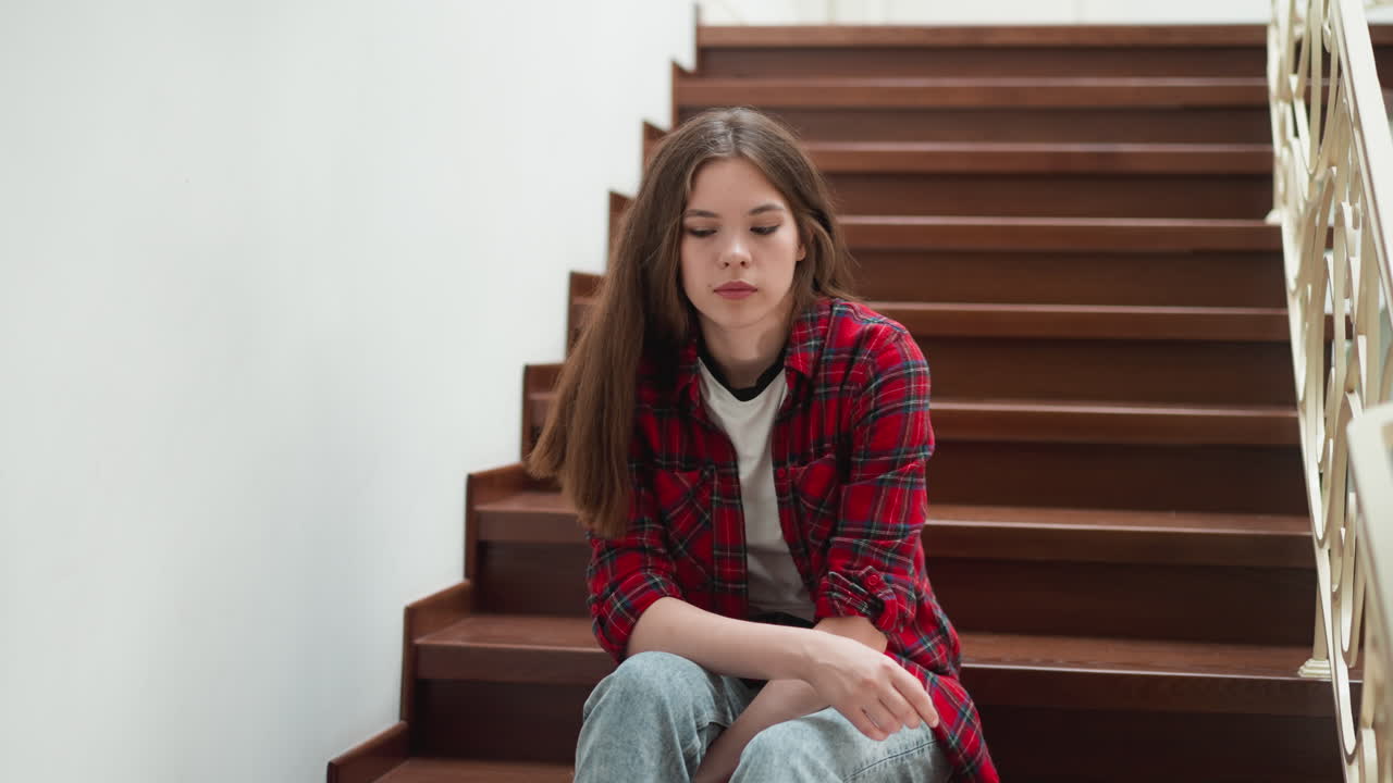 Shy woman sits on building staircase. Student with obsessive thoughts about future tests sits on steps. Lady in casual clothes with nervous expression