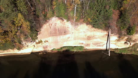 aerial view of a riverbank with trees and autumn foliage in the background