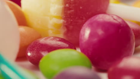 colorful dragee candies, lollipops, bonbons on white background, move in circle, side view close-up. summer bright texture studio shot for store, supermarket. mix of children's sweets made of sugar.
