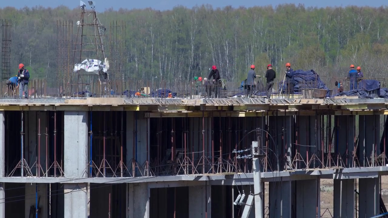 Large construction site with buildings under construction and multi-storey residential homes timelapse. Workers in action on blue sky background. Housing renovation concept