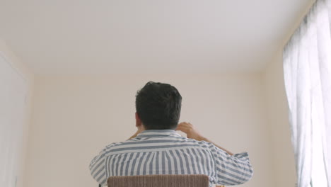 A-Back-View-Of-A-Guy-Sitting-Showing-Frustration-And-Confusion-And-Grabbing-His-Own-Hair