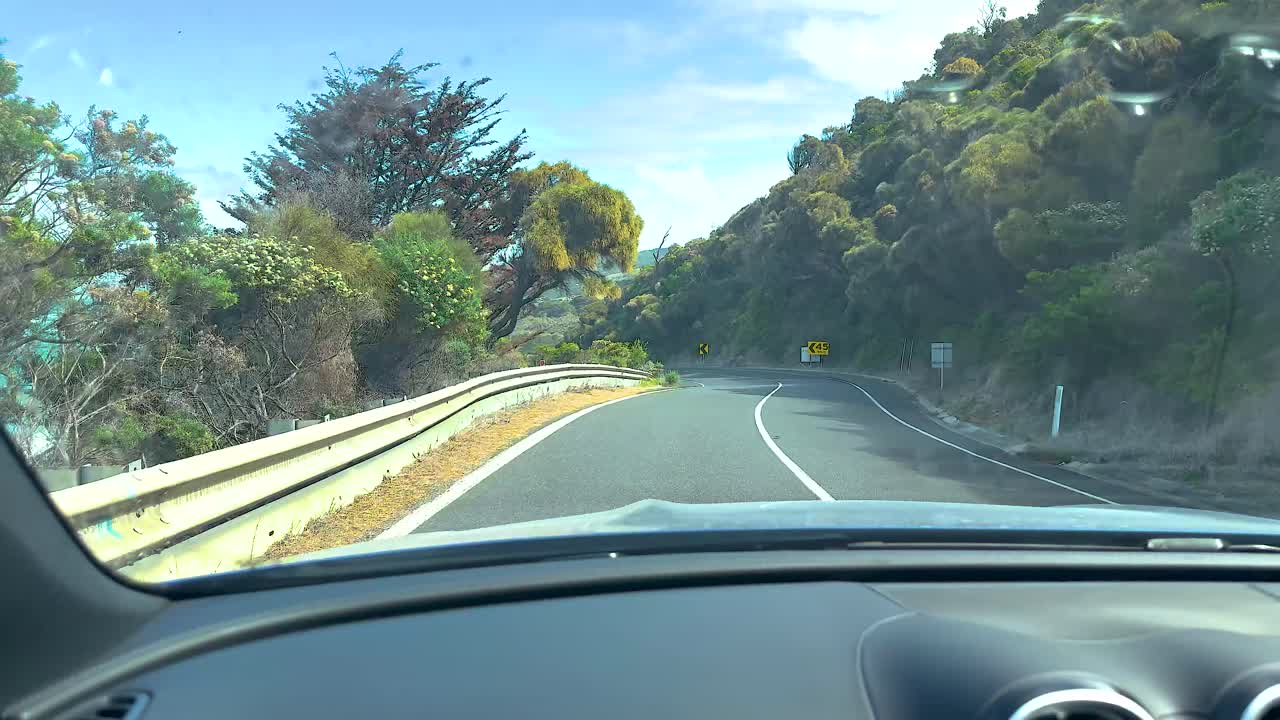 A car journey along the Great Ocean Road, showcasing coastal views and winding roads under bright daylight