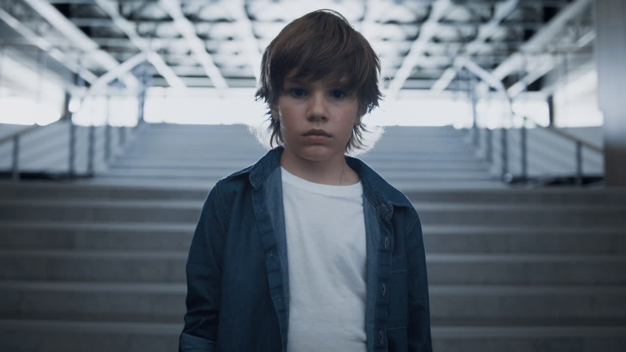 우울한 학교 소년은 빈 계단에서 혼자 서 있습니다. 두려운 눈