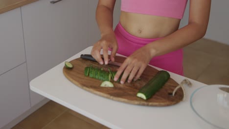 woman cutting cucumber in the kitchen