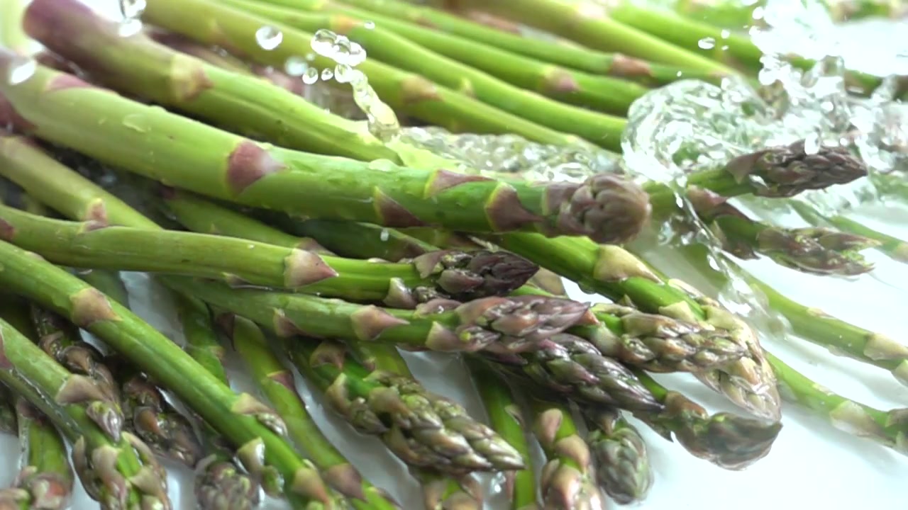 Asperges vertes fraîches. Éclaboussures d'eau. Ralenti