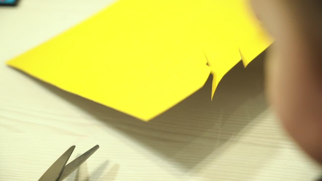 Child cuts paper with scissors. Early childhood education.