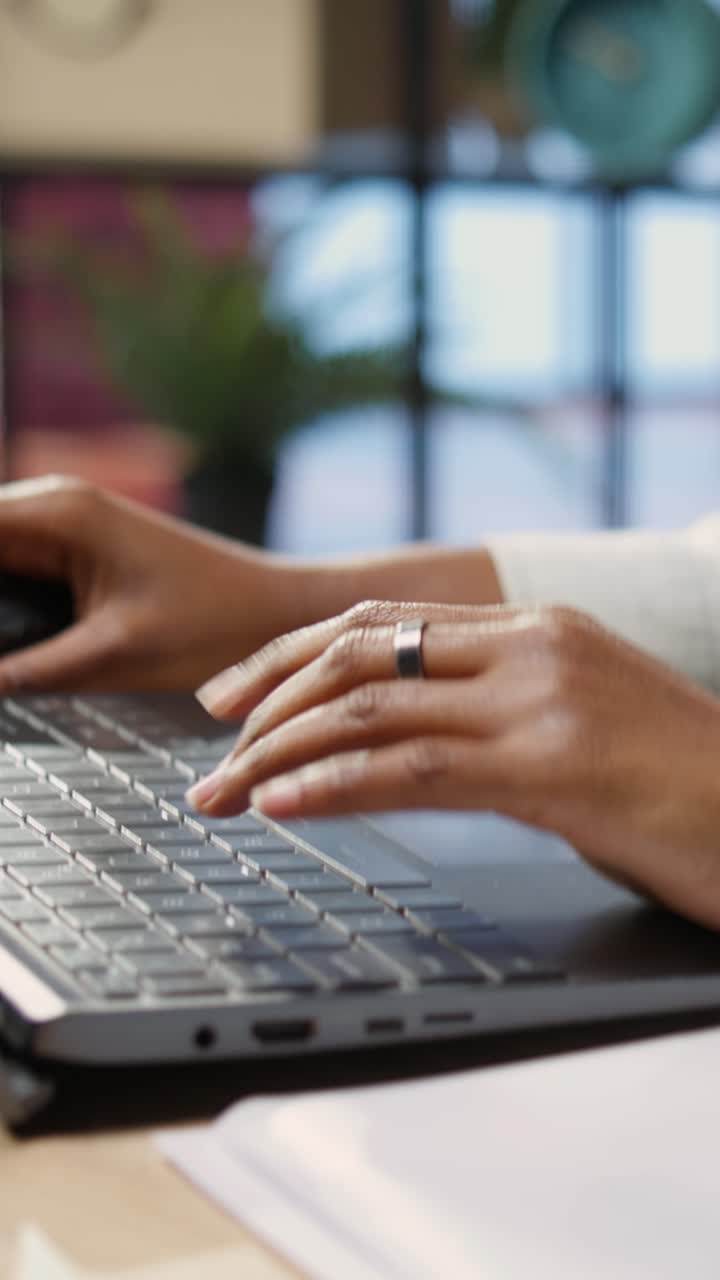 Vertical video Teleworker typing on notebook keyboard in home office, close up