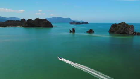 drone rastreando un barco turístico navegando cerca de pequeñas islas de acantilados de langkawi, imágenes en cámara lenta