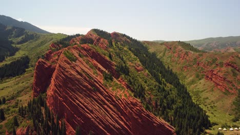 Drone-footage-would-showcase-red-mountains,-lush-green-trees,-and-bright-sunny-day