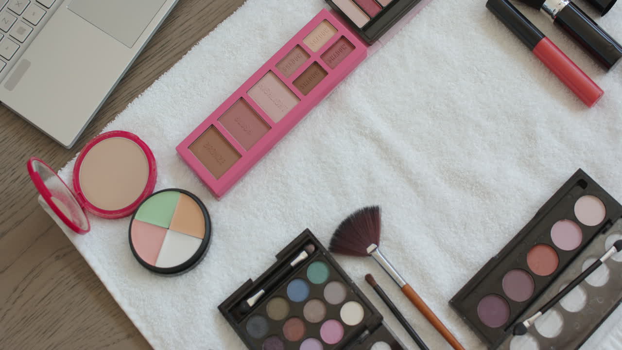 Makeup palettes and brushes arranged on towel for home beauty routine