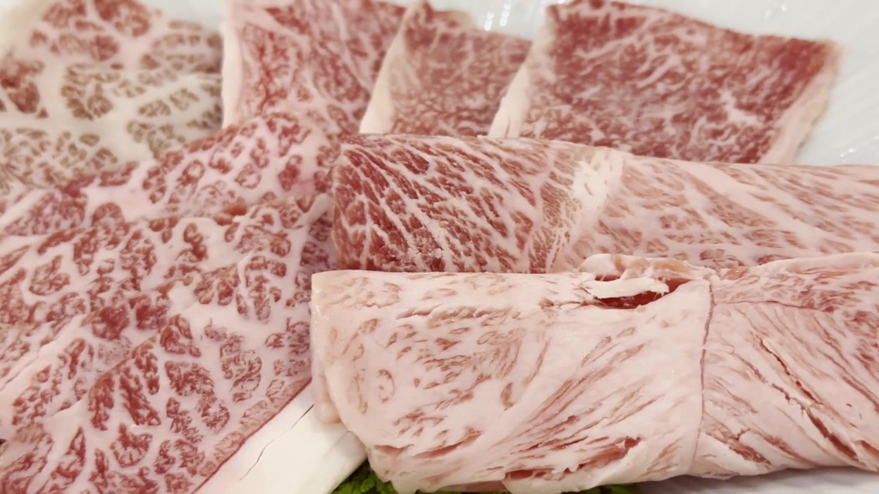 Primer plano de rebanadas de carne de res Wagyu A5 premium dispuestas en un plato de servir, destacando un marmoleado excepcional y una presentación elegante para una cena gourmet.