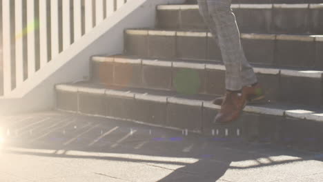 Animation-of-glowing-lights-over-low-section-of-businessman-walking-down-steps