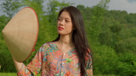 portrait-of-young-female-asiatic-farmer-moving-air-with-rice-hat-while-working-in-agricultural-field